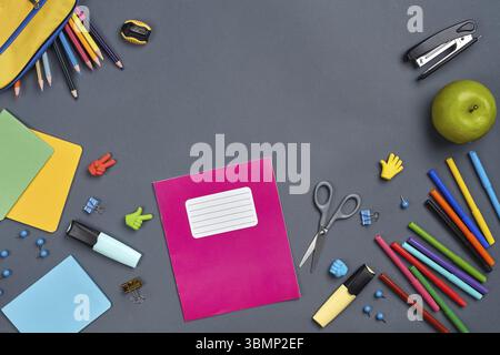 Flat lay photo of a workspace table with school accessories, such as felt-tip pens, two markers, yellow pencil case, erasers, buttons, paper clips, sc Stock Photo