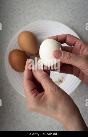 Caucasian female peeling hard boiled eggs closeup view from above Stock Photo
