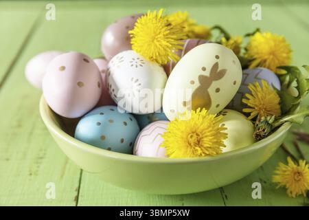 Happy Easter Holidays. Handmade Easter colorful eggs and spring flowers dandelions on a rustic wooden table. Easter composition Stock Photo