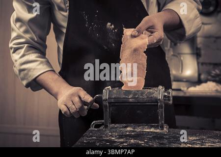 The chef makes fresh spaghetti from scratch. Wooden table. Photo in brown tones. Kitchen Stock Photo