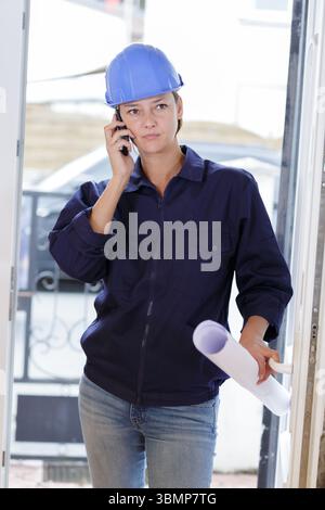 woman builder with blueprints using smart phone Stock Photo