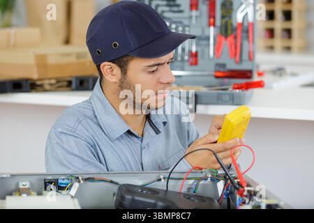 male hands measuring voltage in electrical wall recepticle Stock Photo
