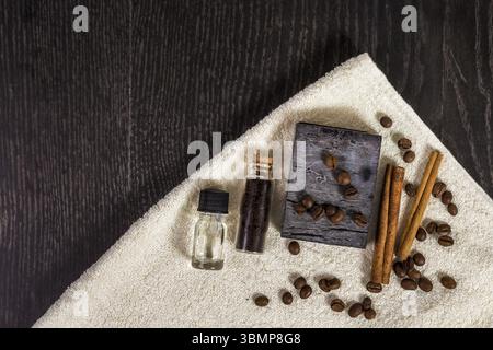 Spa set in brown: natural soap, aromatic oil, cinnamon sticks, coffee beans and towel on wood background. Top view. Space for your text Stock Photo