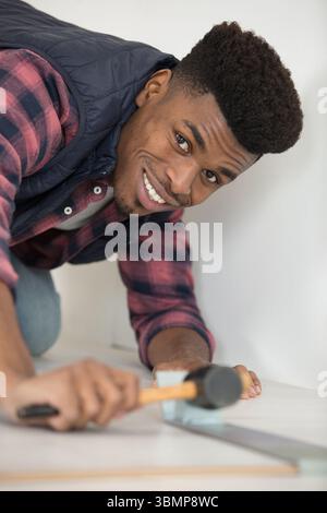 young man using hammer to knocking in flooring Stock Photo
