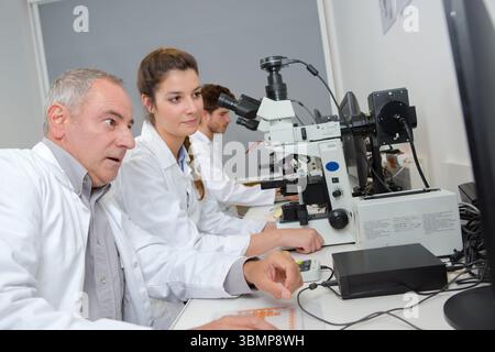 scientists working attentively with microscope in laboratory Stock Photo