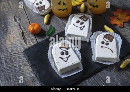 Homemade baked halloween party. Funny cookies in white chocolate glaze ghost on a wooden table. Copy space Stock Photo