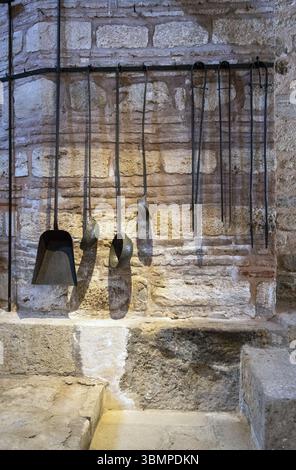 Old metallic kitchenware hanging on a brick wall in a medieval environment Stock Photo