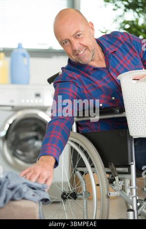 disabled man on wheelchair doing laundry Stock Photo