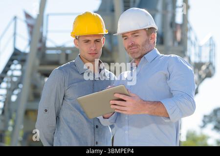 male construction workers discussing over digital tablet Stock Photo