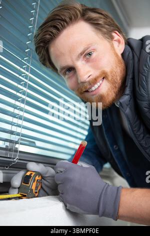 portrait of a handyman measuring a window sill Stock Photo