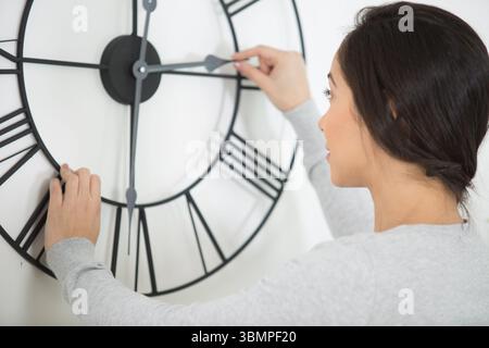 woman setting the time on a wall clock Stock Photo