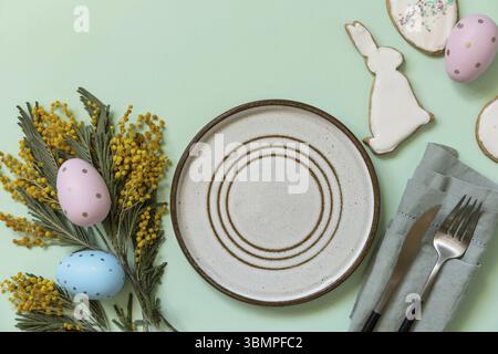 Table setting for Easter dinner with easter eggs and mimosa on a pastel background. Easter decorations concept. View from above. Copy space Stock Photo