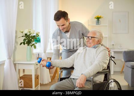 Elderly Patient In Wheelchair Doing Exercise With Dumbbell And Physiotherapist Stock Photo