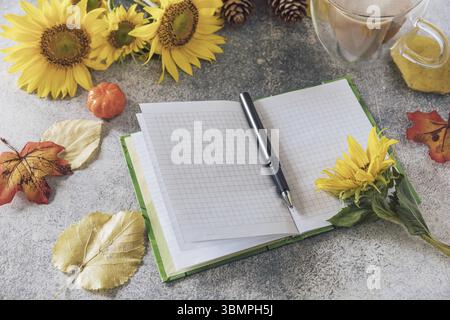 Good Morning. To do list concept. A bouquet of large sunflowers, coffee cup and empty notebook on a stone table Stock Photo