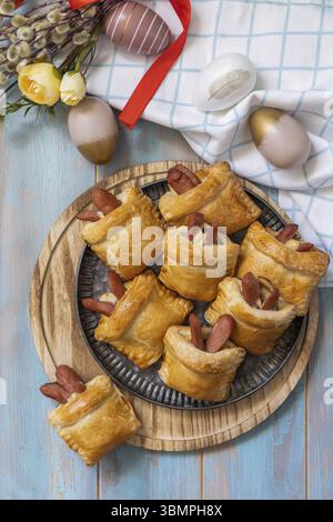 Buns in the form of an Easter rabbit and colored eggs on a wooden table. Traditional Easter symbols and food. View from above Stock Photo