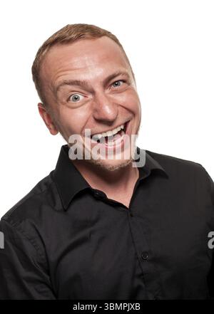 Young blond man in a black shirt is making faces at the camera, isolated on a white background Stock Photo