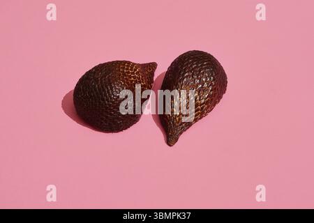 Close up high quality image of bronze salacca halves, fruit composition on coral pink background. Mockup, flat style Stock Photo