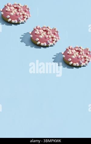 Concept food design with tasty pink glazed donut with white flakes on blue pastel background top view pattern. Mock up. flat lay style Stock Photo