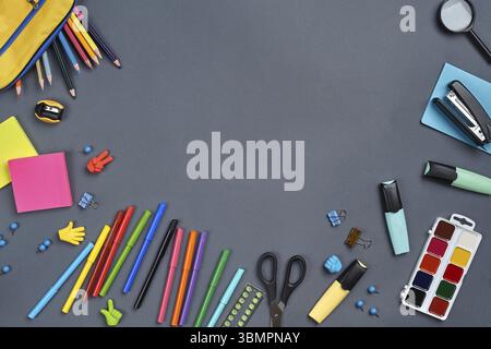 Flat lay photo of a workspace desk with school stationers, such as felt-tip pens, three markers, yellow pencil case, erasers, buttons, paper clips, sc Stock Photo