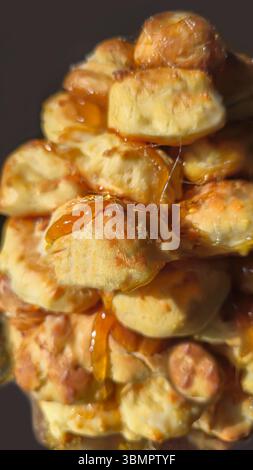 Croquembouche on a light plate covered with caramel. Eclairs with homemade custard cream. Homemade pastries Stock Photo