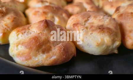 Croquembouche on a light plate covered with caramel. Eclairs with homemade custard cream. Homemade pastries Stock Photo