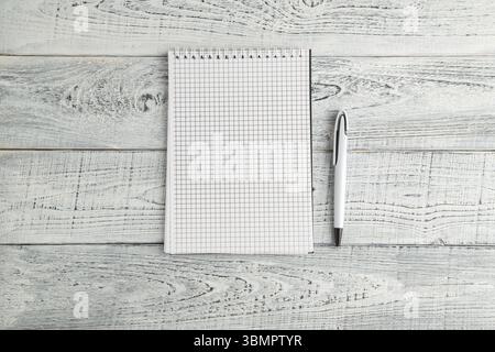White paper Notepad and white pen on vintage shabby white wooden background Stock Photo