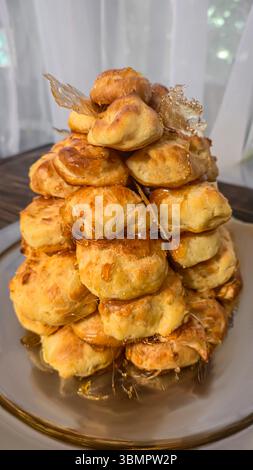 Croquembouche on a light plate covered with caramel. Eclairs with homemade custard cream. Homemade pastries Stock Photo