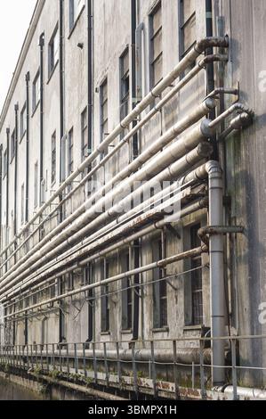 Old pipes on the wall outside of an old abandoned factory Stock Photo