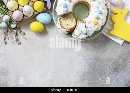 Glazed easter lemon cake decorated with confectionery and mini chocolate eggs candy on gray stone background. Happy Easter holidays, tasty dessert. Vi Stock Photo