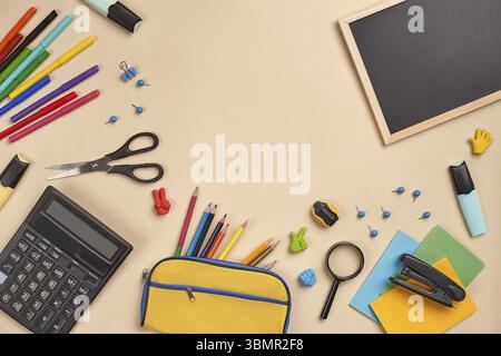 Bright flat lay photo of a workspace desk with school supplies, such as three markers, colored pencils, yellow pencil case, felt-tip pens, magnifier, Stock Photo
