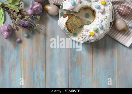 Glazed easter lemon cake decorated with confectionery and mini chocolate eggs candy on a wooden table. Happy Easter holidays, tasty dessert. View from Stock Photo