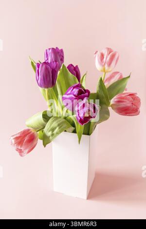 Bouquet of pink and purple tulips with colorful quail eggs over pink background. Mother's day holiday concept Stock Photo