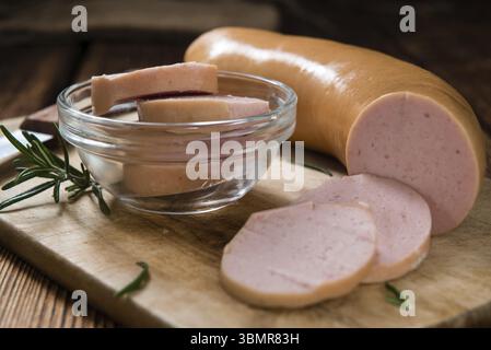 Sliced Baloney (close-up shot) on dark wooden background Stock Photo