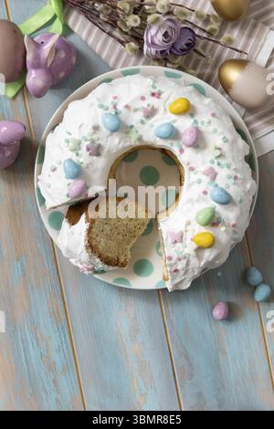 Glazed easter lemon cake decorated with confectionery and mini chocolate eggs candy on a wooden table. Happy Easter holidays, tasty dessert. View from Stock Photo