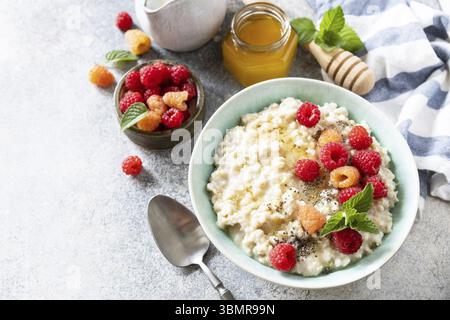 Healthy diet breakfast. Oatmeal porridge in ceramic bowl decorated with fresh berries raspberries and chia seeds served with honey. Copy space Stock Photo