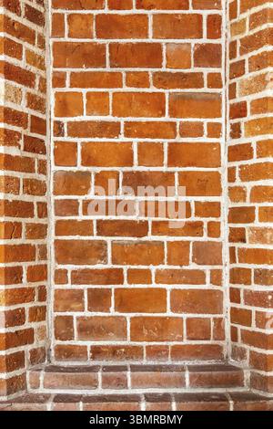 Recess arch frame in old brick wall. Detail of decorative portal in a red brick wall. Recess in a brick wall. Red brick masonry with recesses Stock Photo