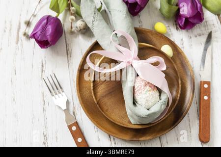 Easter table setting with painted eggs, purple tulip and cutlery on festive table. Table setting for Happy Easter day Stock Photo