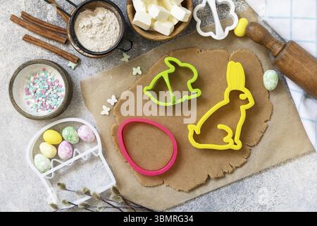 Easter baking ingredients background. Flour, eggs, milk, sugar, butter and kitchen utensils for baking on a stone table. View from above. Copy space Stock Photo