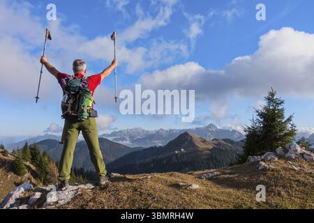 Hiker cheering elated and blissful with arms raised in the sky after hiking Stock Photo