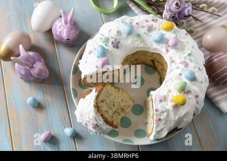 Glazed easter lemon cake decorated with confectionery and mini chocolate eggs candy on a wooden table. Happy Easter holidays, tasty dessert Stock Photo