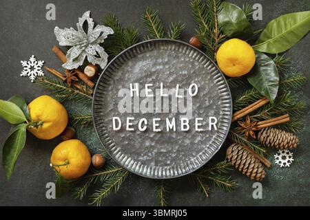 Hello December text. Winter composition with fir branches, cones and tangerines. Cozy winter mood. Seasons greeting card Stock Photo
