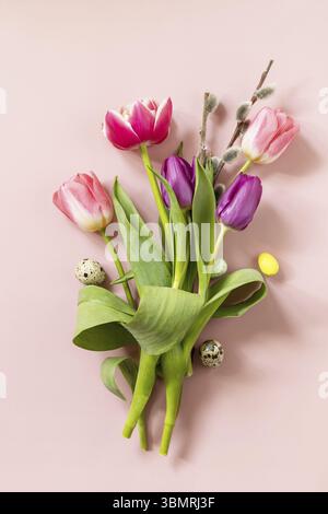 Easter composition with colorful Easter eggs and spring flowers tulips over pink background. Spring and Easter holiday concept. Top view flat lay Stock Photo