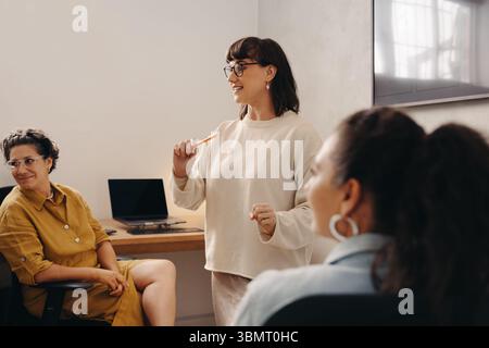 A confident team leader engages colleagues in a productive discussion within a bright workspace. Stock Photo