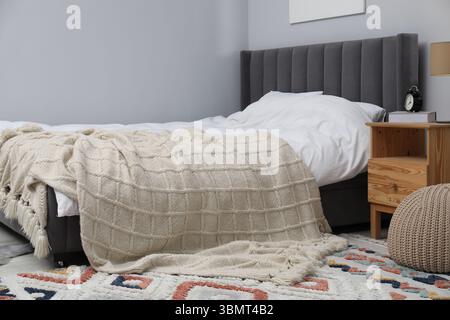 Beige woolen blanket on bed in room Stock Photo