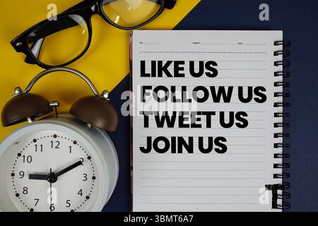 Like Us Follow Us Tweet Us Join Us text written on notepad with alarm clock on blue background Stock Photo