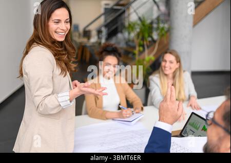 Smiling female architect gesturing and explaining ideas to businessman while collaborating in office during meeting Stock Photo