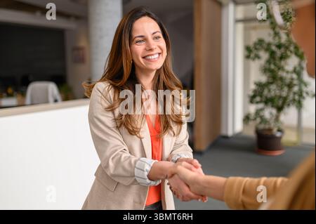 Smiling female lawyer shaking hands with client in office while beginning a successful collaboration Stock Photo