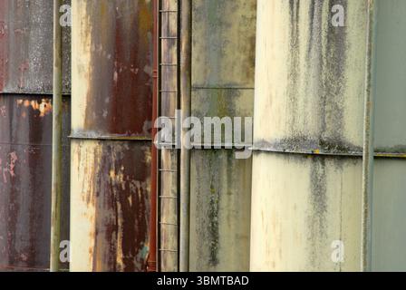 Abstract close-up of weathered and rusty industrial silos with a ladder. Stock Photo