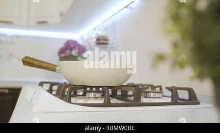 Sleek frying pan on a stovetop in a modern kitchen, ready for delicious cooking. Stainless steel pan stands out against clean white background, adding Stock Photo