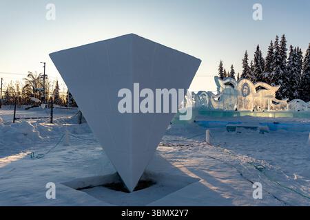 Fairbanks, USA - February 21, 2023: golden hour sunset light on inverse pyramid sculpture at World Ice Art Championships, ice sculpting contest and festival Stock Photo